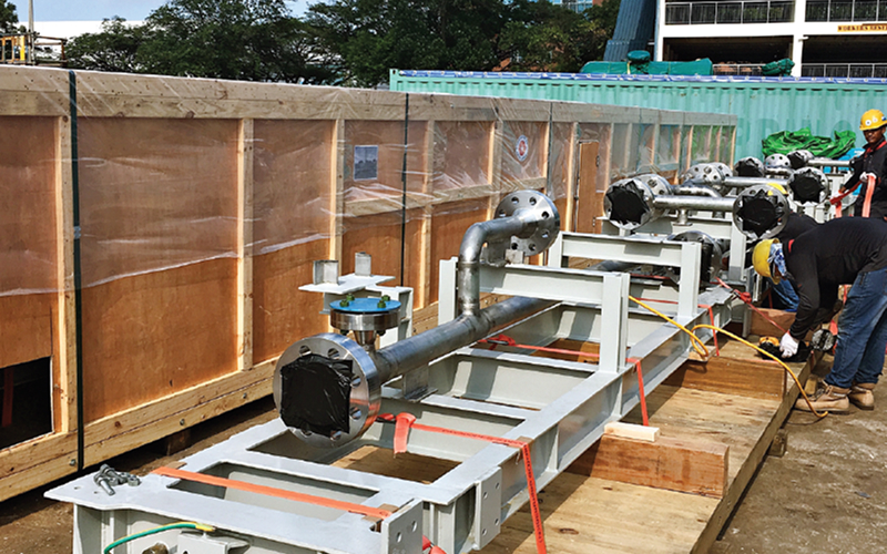 Workers securing heavy industrial equipment inside wooden shipping crate.
