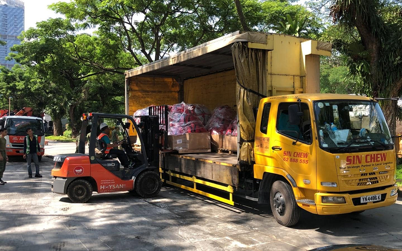 Forklift loading cargo onto Sin Chew delivery truck securely.