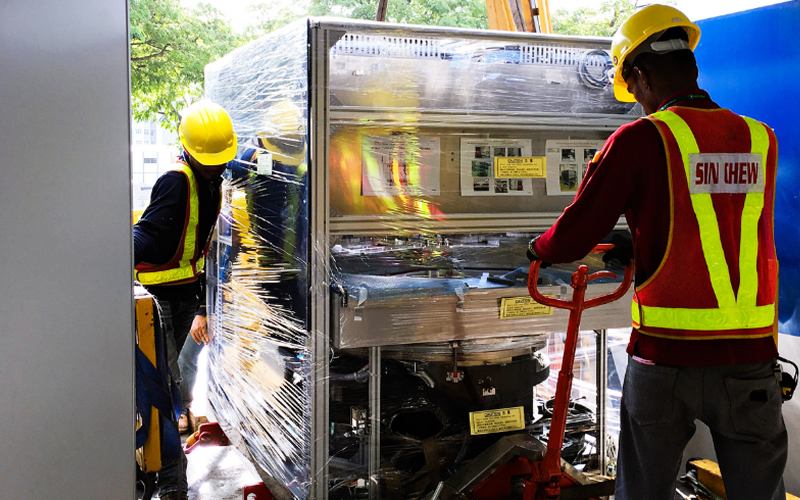Workers-moving-wrapped-heavy-machinery-to-enhance-logistics-efficiency